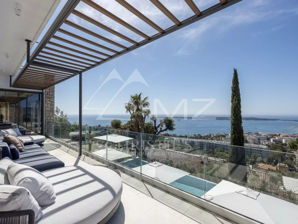 Vue panoramique depuis une terrasse d'une villa contemporaine à Cannes, avec piscine et mer en arrière-plan.