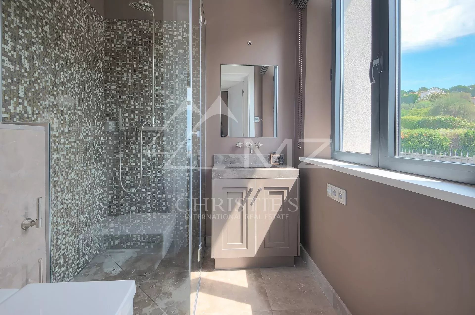 Salle de bains élégante Salle de bains moderne avec douche et lavabo, murs carrelés en mosaïque, lumière naturelle à travers la fenêtre.