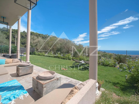 Vue d'une élégante demeure à Cannes avec jardin et piscine, offrant une vue dégagée sur la mer.