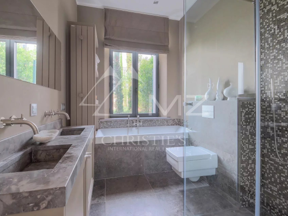 Salle de bains moderne avec baignoire et douche, murs en carrelage mosaïque.