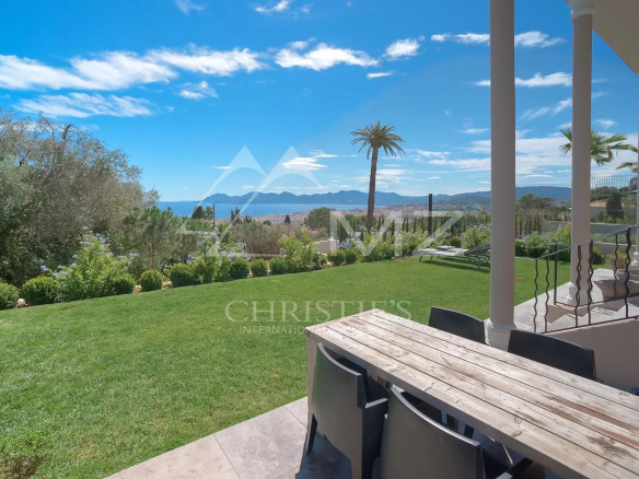 Vue d'une terrasse avec table en bois et jardin, vue sur la mer à Cannes.