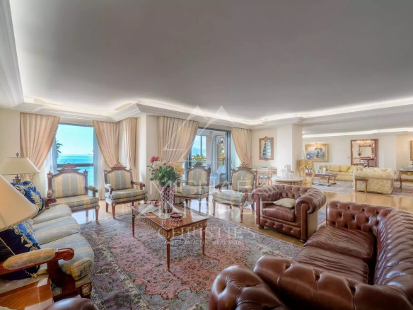 Salon spacieux d'un appartement de luxe à Cannes avec vue mer et grandes fenêtres.