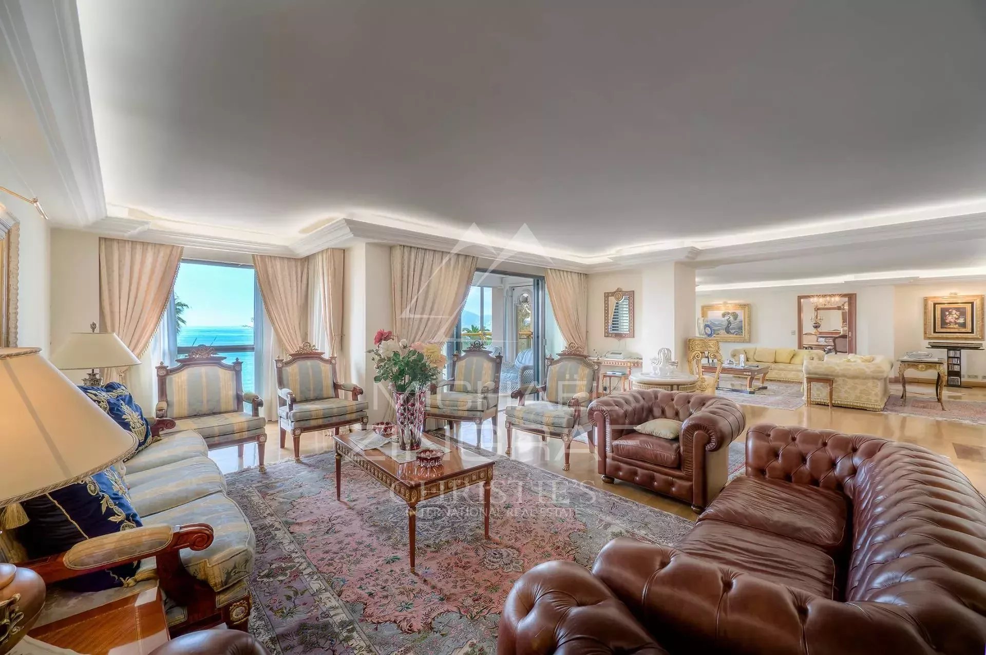Appartement d’exception à Cannes Salon spacieux d'un appartement de luxe à Cannes avec vue mer et grandes fenêtres.