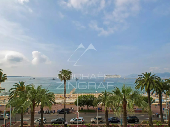 Vue panoramique sur la mer depuis un appartement à Cannes Croisette avec palmiers au premier plan.