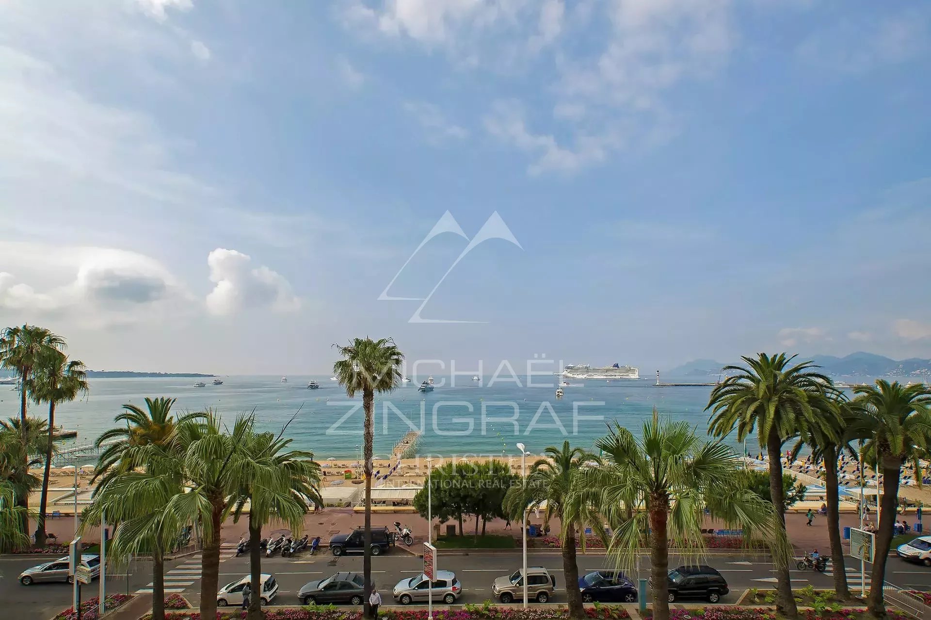 Vue depuis un appartement d’exception à Cannes Vue panoramique sur la mer depuis un appartement à Cannes Croisette avec palmiers au premier plan.
