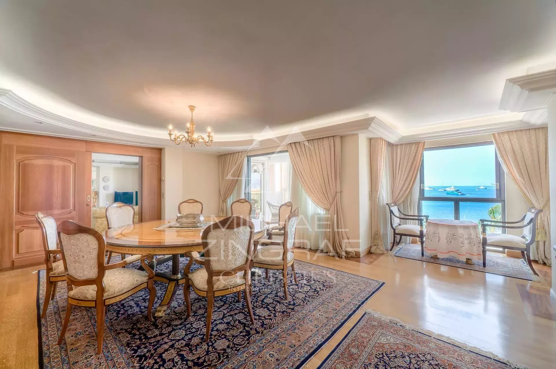 Appartement d’exception à Cannes Intérieur d'un appartement de luxe à Cannes avec vue mer, salle à manger et fenêtres ouvertes sur la terrasse.