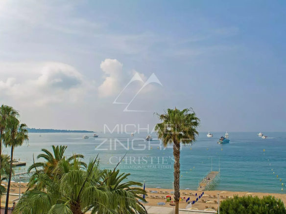 Vue panoramique sur la mer depuis un appartement à Cannes Croisette avec palmiers au premier plan.