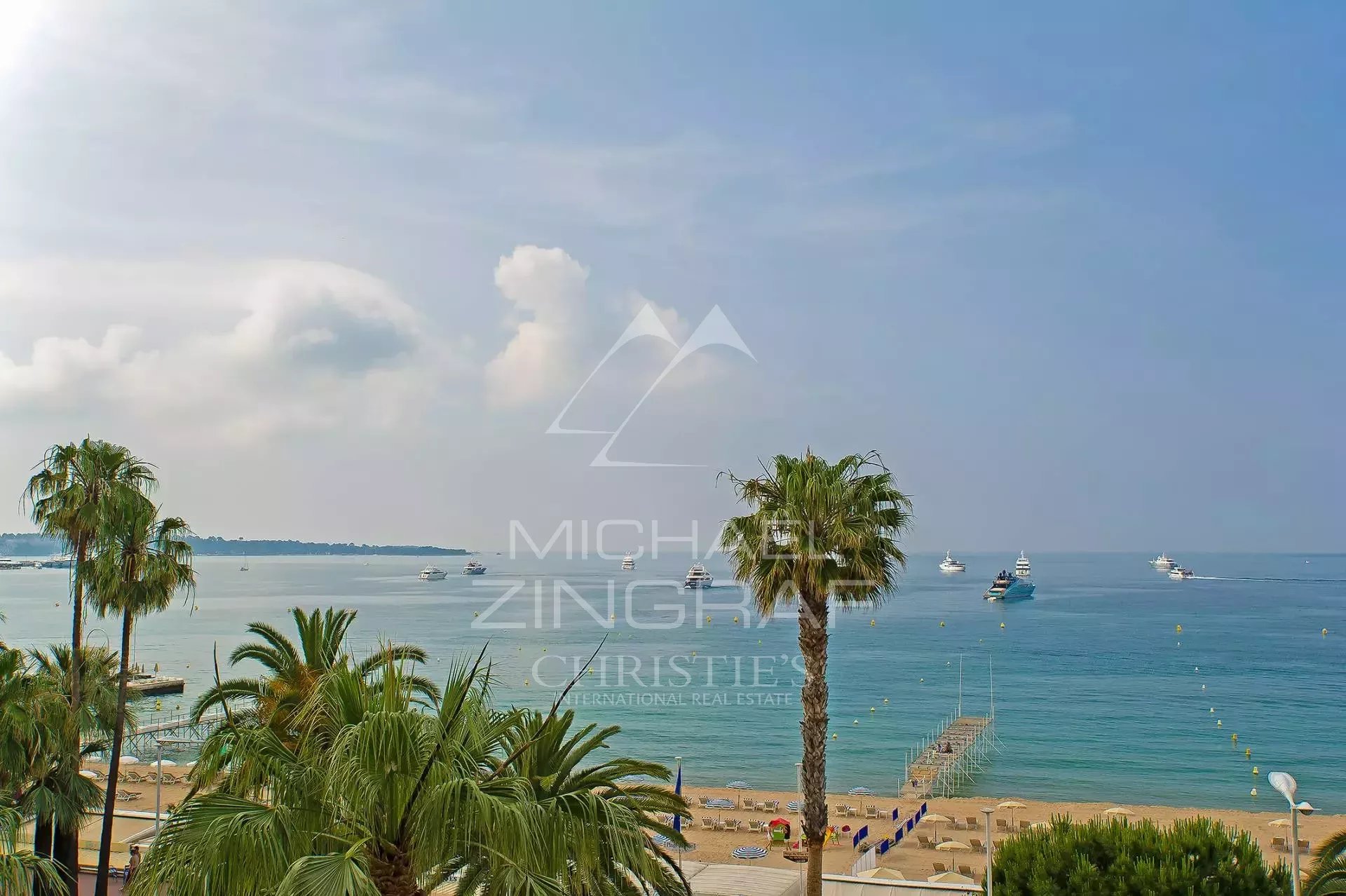 Vue sur la mer à Cannes Croisette Vue panoramique sur la mer depuis un appartement à Cannes Croisette avec palmiers au premier plan.