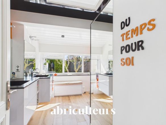 Bright modern kitchen showroom with white cabinets, black countertops, and large windows; orange and black wall letters spell 'DU TEMPS POUR SOI' on the right, with 'abriculteurs' watermark at the bottom.