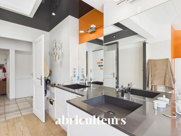 Modern bathroom vanity with two black sinks, mirrored cabinets, and orange wall accents.