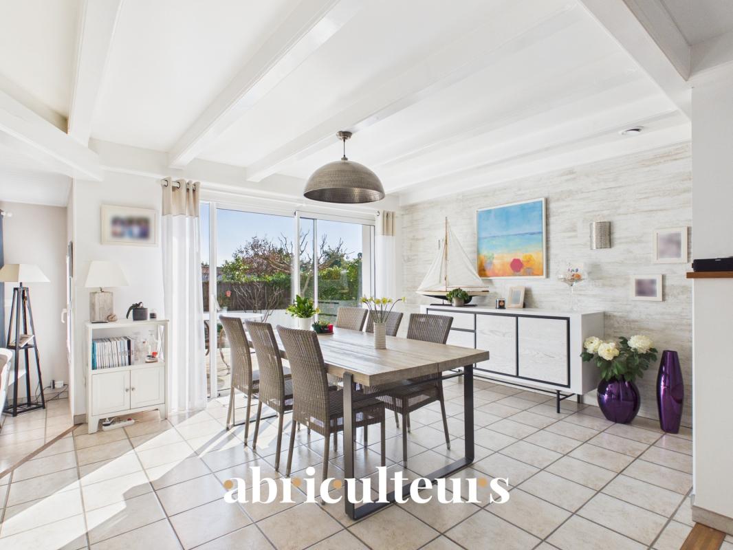 Bright open dining room with a wooden table, eight wicker chairs, and sliding glass doors to a sunny garden exterior, plus a modern sideboard and sailboat model.