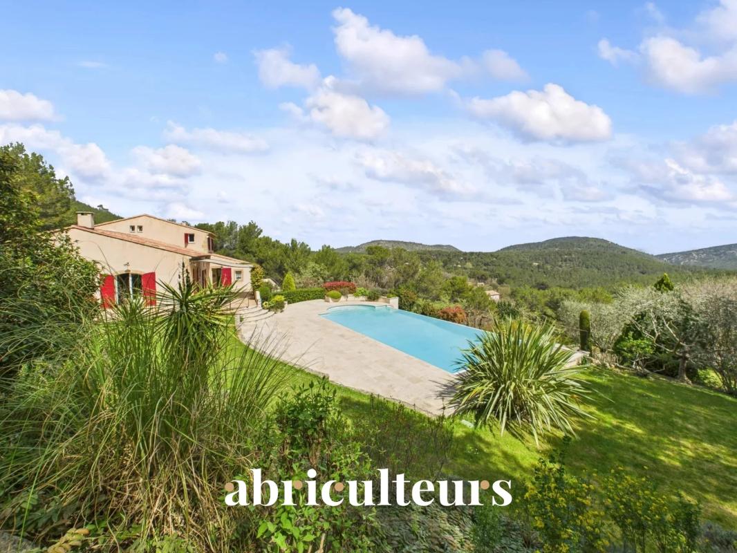 Stone house with red shutters beside a long rectangular pool, set in a green hillside landscape; the word 'abriculteurs' is overlaid on the image.