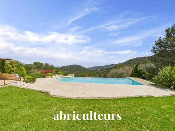 Backyard with a rectangular pool, stone patio, green lawn, and distant hills under a blue sky; the word 'abriculteurs' is overlaid at the bottom.