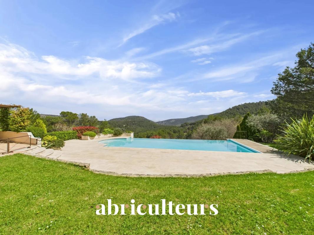 Backyard with a rectangular pool, stone patio, green lawn, and distant hills under a blue sky; the word 'abriculteurs' is overlaid at the bottom.