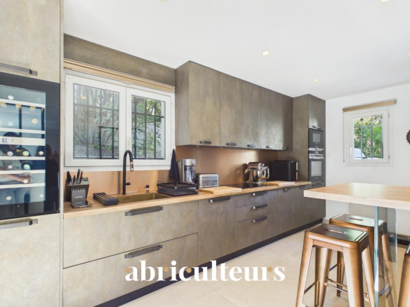 Modern kitchen with matte concrete cabinets, wooden countertop, stainless appliances, and a wine fridge on the left.