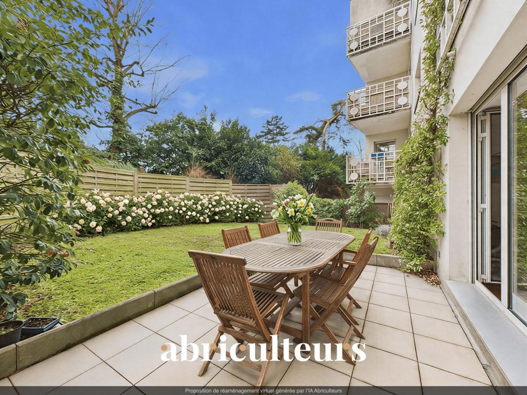 Patio with a wooden dining table and six chairs, a vase of flowers, on a tiled terrace beside a lawn and white rose hedge.
