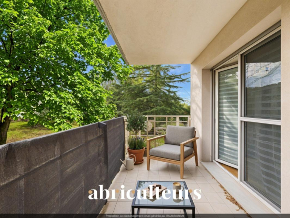 Sunny apartment balcony with a gray cushioned chair, glass-top table, potted plants, and lush trees beyond the railing.