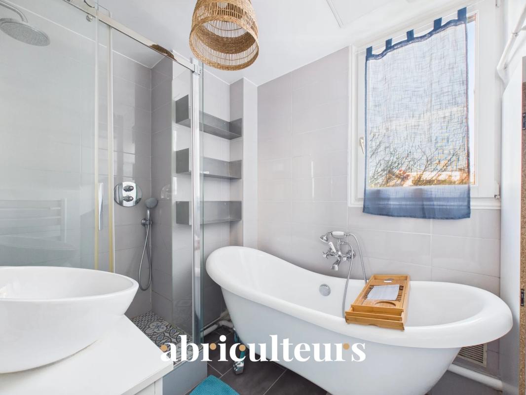 Bathroom of an apartment in the 16th arrondissement of Paris Modern bathroom with freestanding bathtub and shower, natural light.