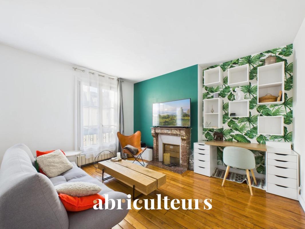 Living room of an apartment in the 16th arrondissement of Paris Bright living room of a through apartment with a green wall and a desk area.