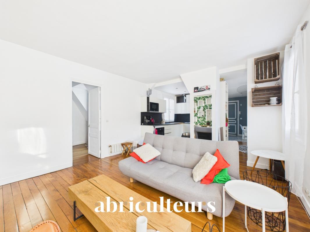 Apartment with windows on both sides in the 16th arrondissement of Paris Interior of a bright apartment with living room, grey sofa and open kitchen.