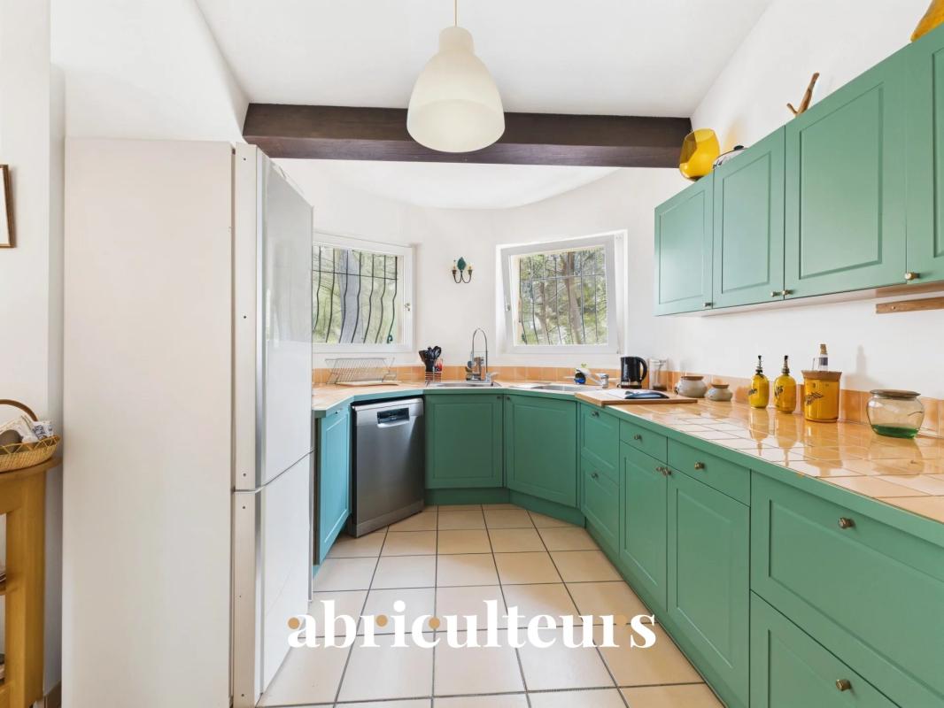 Modern kitchen with green furniture and beige tiles in an architect-designed house.