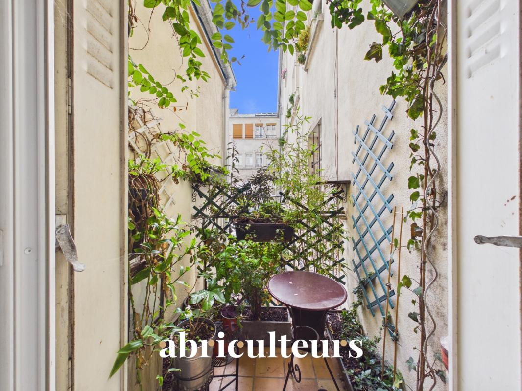 A verdant balcony of an apartment in Paris 11, surrounded by plants and trellises.