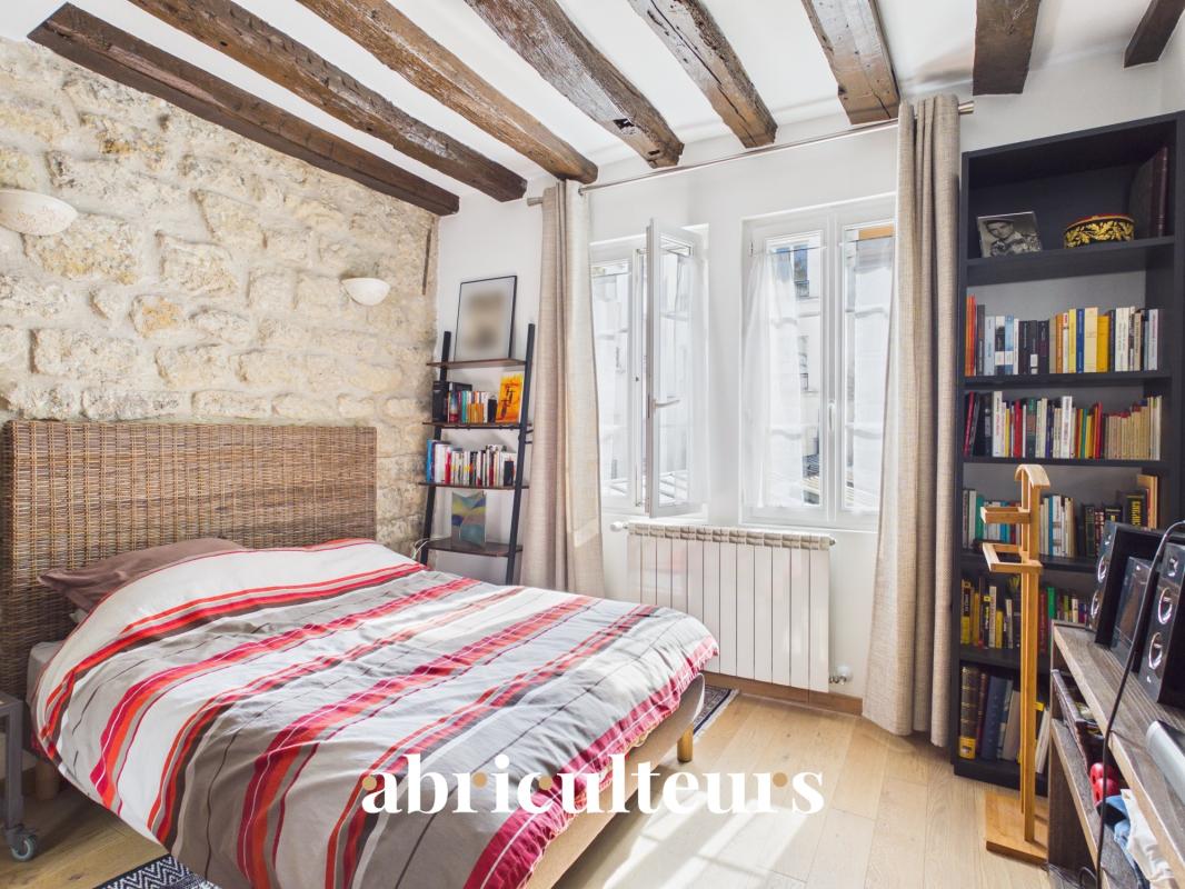 Room in a two-room apartment in Paris 11, with stone walls and a double bed.