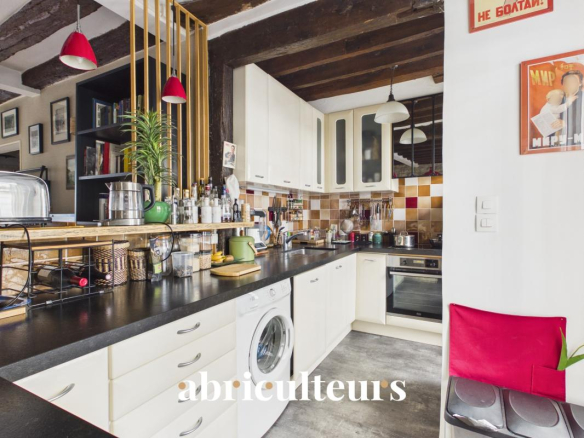 Modern and equipped kitchen in a two-room apartment in Paris 11, with wooden elements and household appliances.