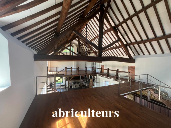 Interior of a renovated house with exposed beams and a mezzanine.