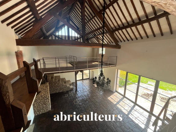 Interior of a renovated house with exposed beam ceiling and large windows in Croisilles.