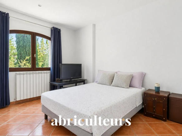 Chambre d'une villa à Les Pennes-Mirabeau avec lit, télévision et fenêtre donnant sur un jardin.
