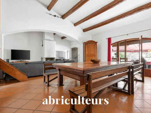 Intérieur d'une villa avec une grande table en bois et des poutres apparentes.