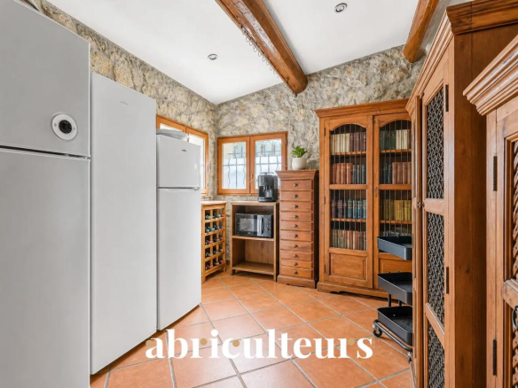 Cuisine d'une villa avec réfrigérateurs, meubles en bois et murs en pierre.