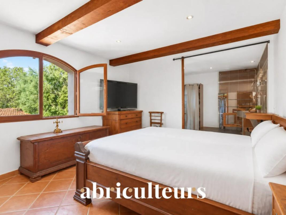 Chambre d'une villa à Les Pennes-Mirabeau avec lit double et fenêtres donnant sur un environnement verdoyant.