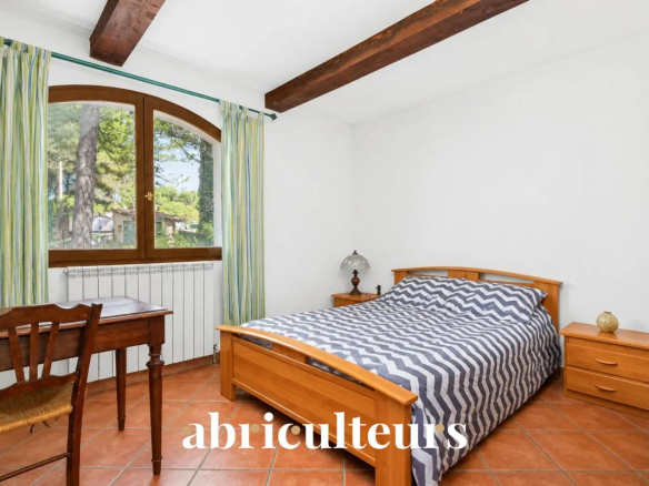 Chambre avec lit double et décoration simple, fenêtres donnant sur un environnement verdoyant.