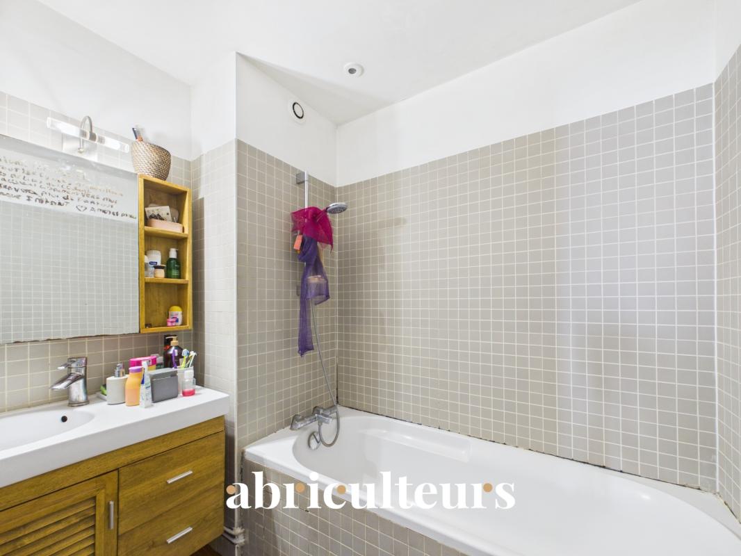 Bathroom with bathtub and sink in a duplex in the 20th arrondissement of Paris.