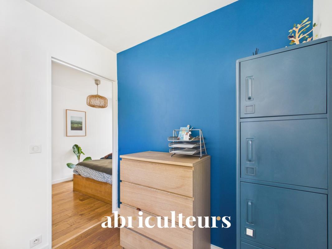 Interior of a duplex in Paris 20th with blue wall and wooden storage unit.
