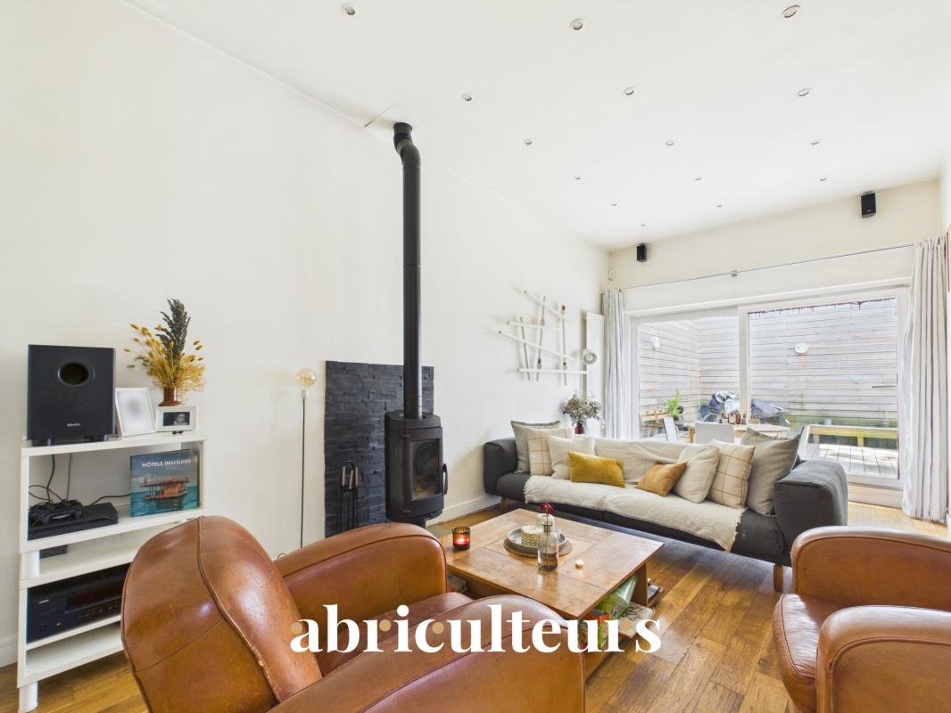 Interior of a duplex in Paris 20th with living room, stove and access to a terrace.