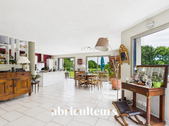 Intérieur d'une maison contemporaine avec salon lumineux et cuisine ouverte, vue sur le jardin.