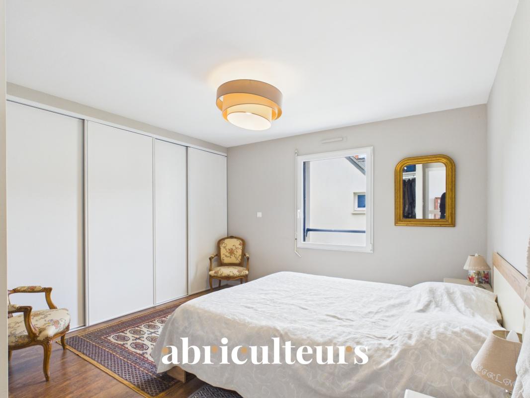Chambre d’une maison contemporaine à Carnac Chambre d'une maison familiale récente avec lit et fauteuil, murs clairs et fenêtre.