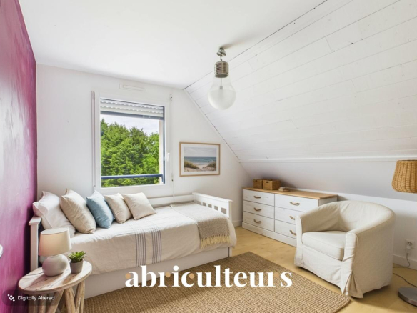 Chambre lumineuse avec lit simple, commode et fauteuil, décorée dans des tons clairs.