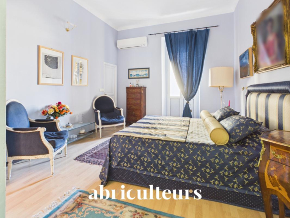 Chambre d'un appartement rénové avec lit, fauteuils et décorations à Nice.