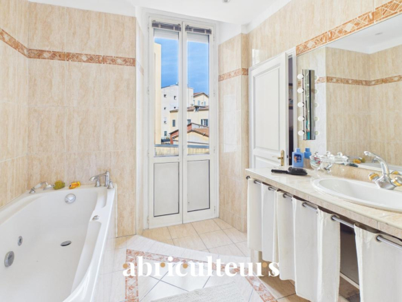 Salle de bain d'un appartement rénové avec baignoire et fenêtres donnant sur l'extérieur.