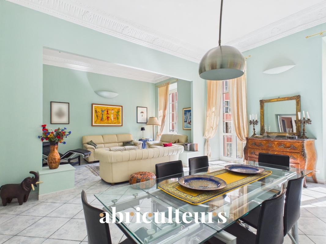 Appartement rénové à Nice Intérieur d'un appartement rénové avec salon et salle à manger, murs verts et mobilier élégant.
