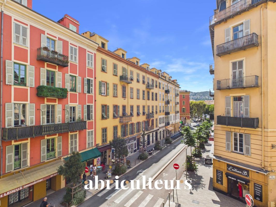 Rue animée à Nice Vue d'une rue animée à Nice avec des bâtiments colorés et des balcons.