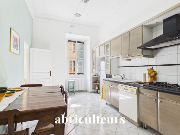 Cuisine rénovée d'un appartement à Nice, avec table en bois et équipements modernes.