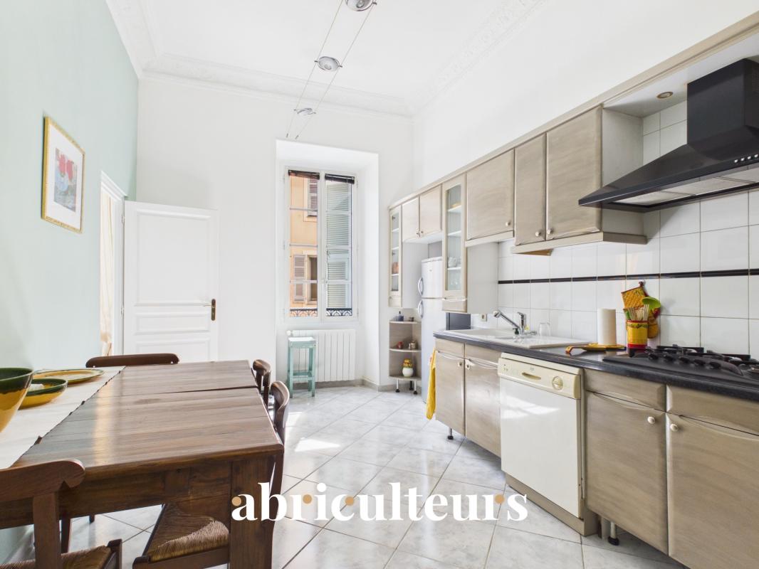 Cuisine d’un appartement à Nice Cuisine rénovée d'un appartement à Nice, avec table en bois et équipements modernes.