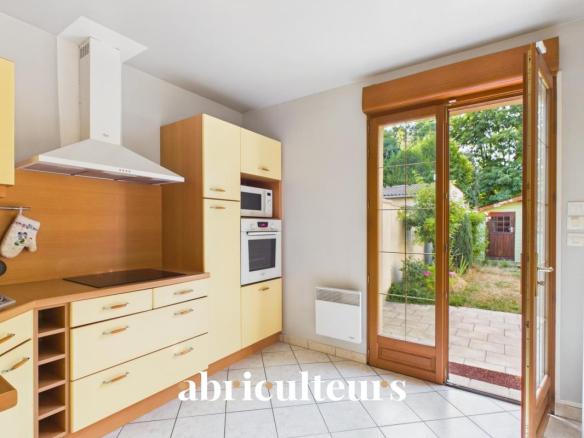 Cuisine moderne avec meubles en bois et accès à un jardin extérieur.