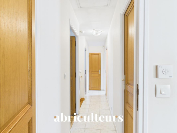 Couloir d'une maison familiale à vendre à Versailles, avec portes et carrelage clair.