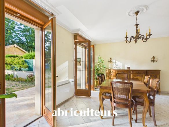Intérieur d'une maison familiale avec une salle à manger et des portes-fenêtres donnant sur le jardin.